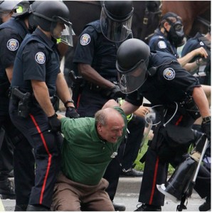 John Pruyn being dragged away by police in riot gear - for sitting on the lawns of Queen's Park listing to speakers at a G20 rally.
